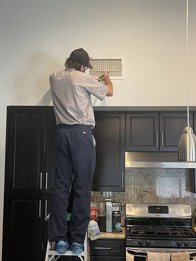 Technician inspecting an air vent during HVAC service in North Greenbush